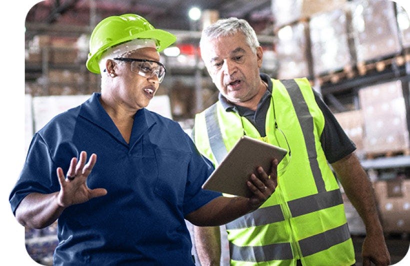 Two employees looking at a tablet in a warehouse