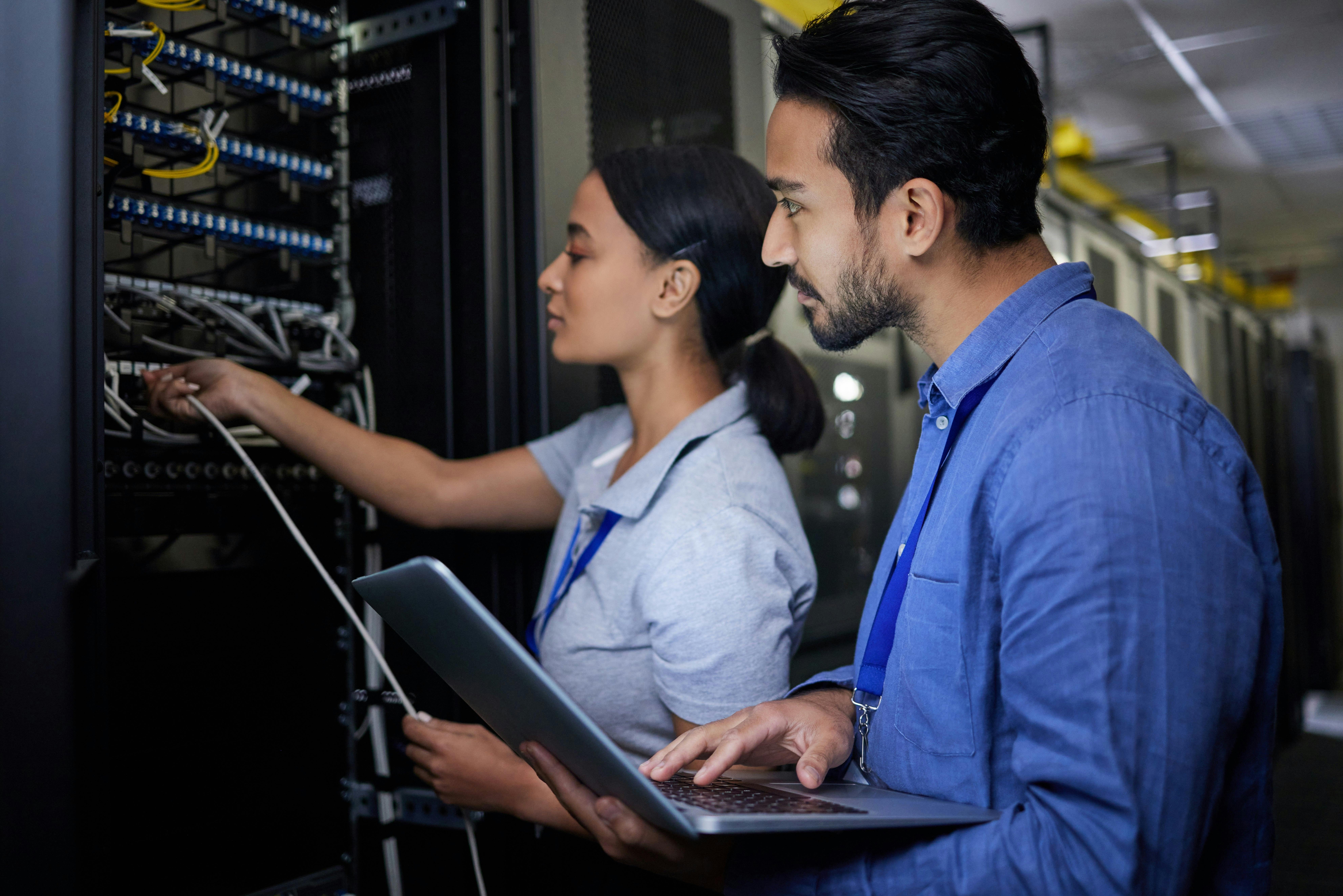 Two people working in a server room